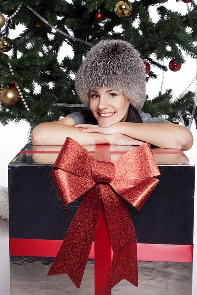 Junge Frau in der Nähe von Neujahrsbaum mit Geschenk — Stockfoto