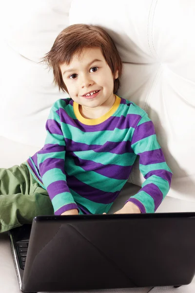 Ładny chłopczyk na kanapie z notebooka — Zdjęcie stockowe