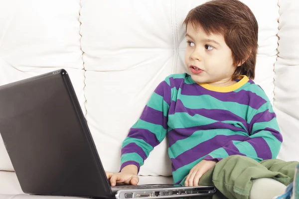 Kleiner hübscher Junge auf dem Sofa mit Notizbuch — Stockfoto