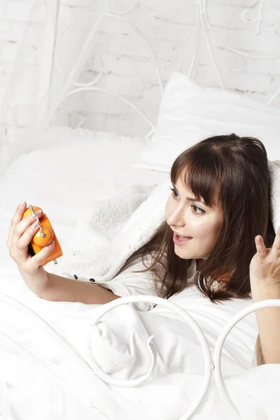 Junge schöne Frau im Bett mit Uhr — Stockfoto