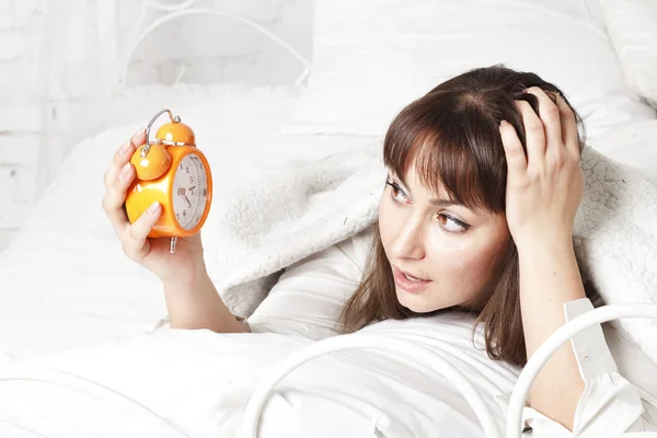 Młoda piękna kobieta w łóżku z zegarem — Zdjęcie stockowe