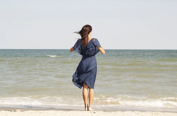 Jonge mooie vrouw aan kust in blauwe jurk — Stockfoto