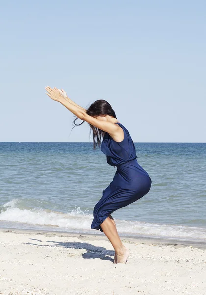 Mladá krásná žena, která dělá jóga u moře v modrých šatech — Stock fotografie