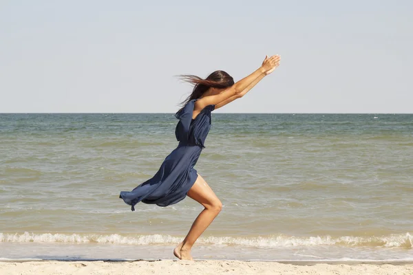 Młoda piękna kobieta robi joga nad morzem w niebieska sukienka — Zdjęcie stockowe