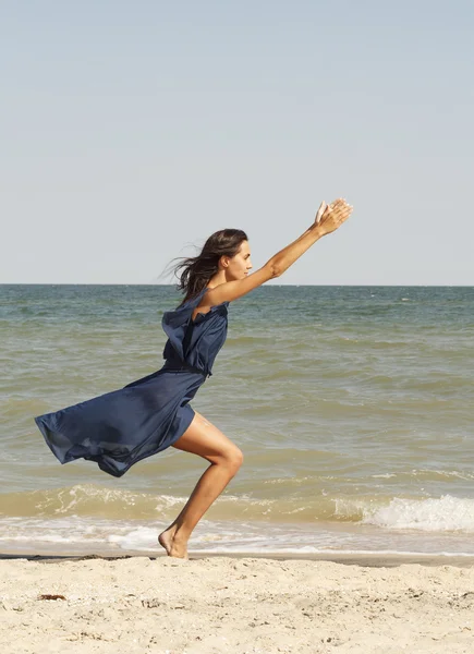 Young beautiful woman doing yoga at seaside in blue dress — Stock Photo, Image