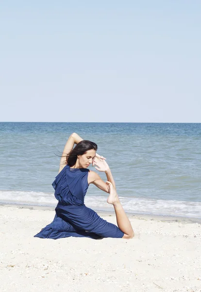 青いドレスの海辺でヨガをやって若い美しい女性 — ストック写真