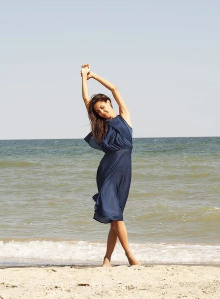 Jonge mooie vrouw aan kust in blauwe jurk — Stockfoto