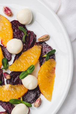 Vejetaryen pancar salatası, şam fıstığı, mozzarella, portakal ve ayçiçeği filizi ile kaplanmış bir tabak.