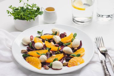 Vejetaryen pancar salatası, şam fıstığı, mozzarella, portakal ve ayçiçeği filizi ile kaplanmış bir tabak.