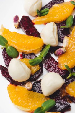 Vejetaryen pancar salatası, şam fıstığı, mozzarella, portakal ve ayçiçeği filizi ile kaplanmış bir tabak.