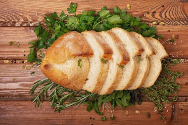 Dikkatlice dilimlenmiş taze ekmek yeşil maydanozun ve kokulu biberiyenin üzerinde yatıyor.