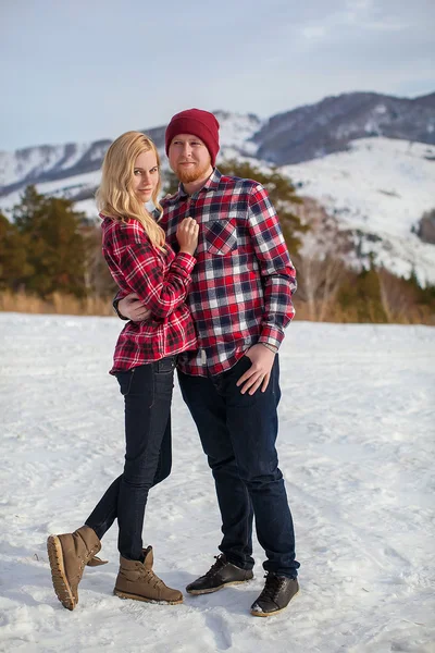 young couple in red shirts in the mountains in winter