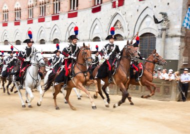 Performance of cavalry on parade before start of annual traditional Palio di Siena horse race in medieval square 