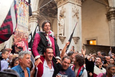 Hayranları ortaçağ meydanında yıllık geleneksel Palio di Siena at yarışında zafer jokey memnun 