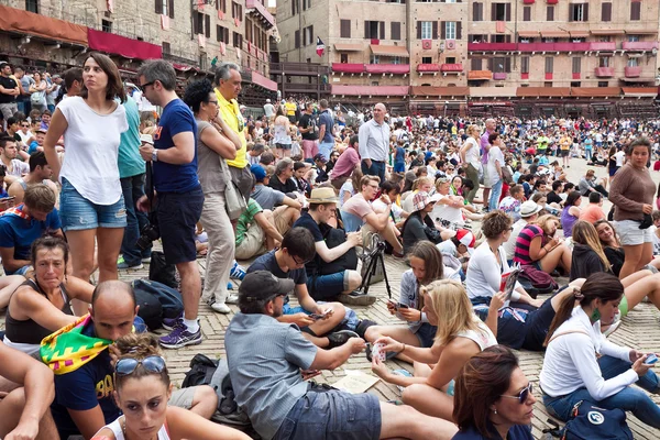 Widzowie wyglądają na początku rocznego tradycyjnego wyścigu koni Palio di Siena w średniowiecznym placu "Piazza del Campo" — Zdjęcie stockowe