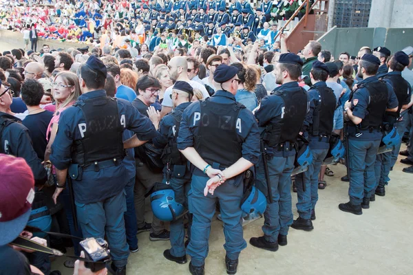 Policja zachować porządek przed rozpoczęciem rocznego tradycyjnego wyścigu koni Palio di Siena w średniowiecznym placu "Piazza del Campo" — Zdjęcie stockowe