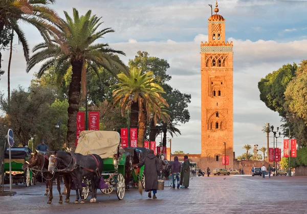 Taxistas en carruajes tirados por caballos alrededor de la mezquita de Koutoubia esperando turistas en Marrakech, Marruecos Imagen De Stock