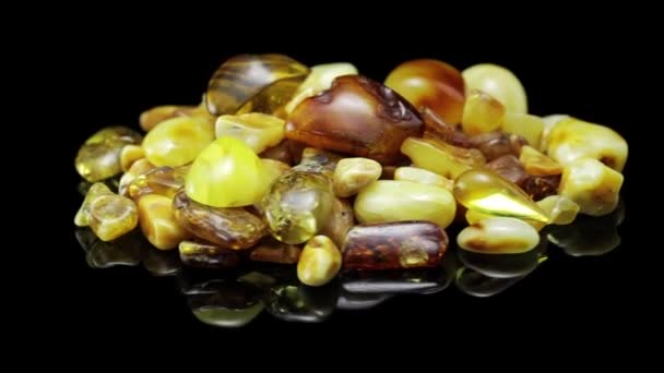 Natural amber. Many pieces of natural raw amber on a black background spining in a circle. — Stock Video