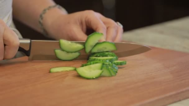 Komkommer wordt gesneden op een snijplank met een mes — Stockvideo