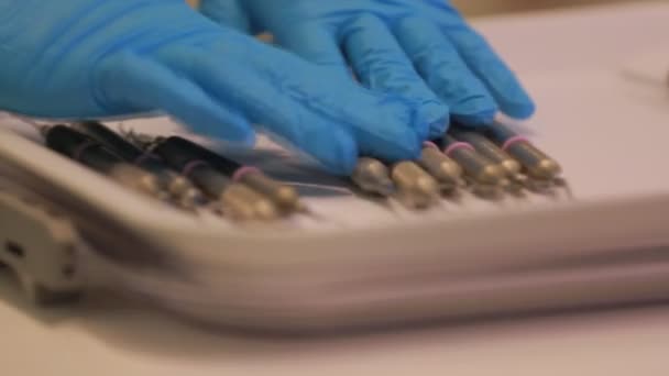Стоматолог выкладывает инструменты на поднос — стоковое видео
