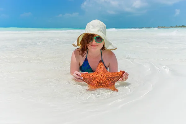 Young woman and starfish on a tropical beach — Stock Photo, Image