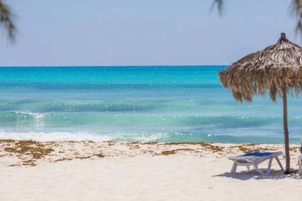Praia exótica com areia branca e guarda-chuvas feitos de folhas de palmeira — Fotografia de Stock