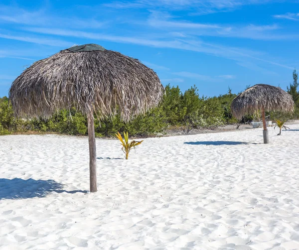 Praia exótica com areia branca e guarda-chuvas feitos de folhas de palmeira — Fotografia de Stock