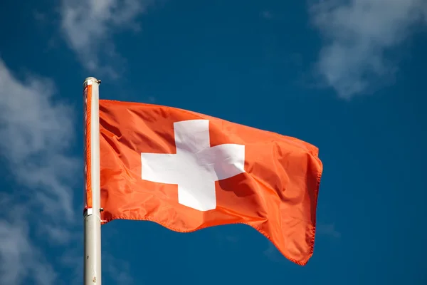 Švýcarská vlajka proti modré obloze — Stock fotografie