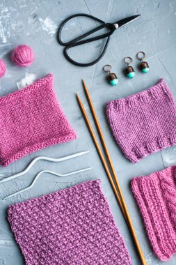 Üst görünüm: örgü aksesuarları ve örgü ürünlerinin örnekleri gri beton bir arka planda yatıyor. Yazı için yer.