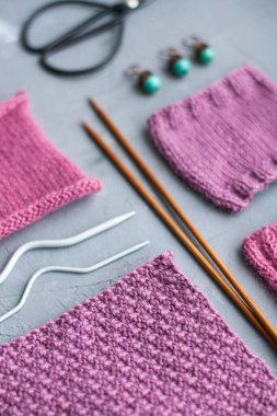 Üst görünüm: örgü aksesuarları ve örgü ürünlerinin örnekleri gri beton bir arka planda yatıyor. Yazı için yer.