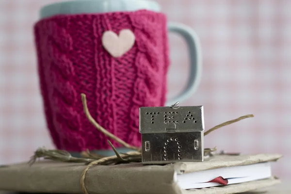 Tazza blu in un maglione rosa in piedi su un vecchio taccuino — Foto Stock