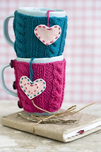 Two blue cups in blue and pink sweater with felt hearts — Stock Photo, Image