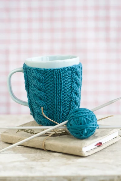 Blue cup in a blue sweater standing on an old notebook — Stock Photo, Image