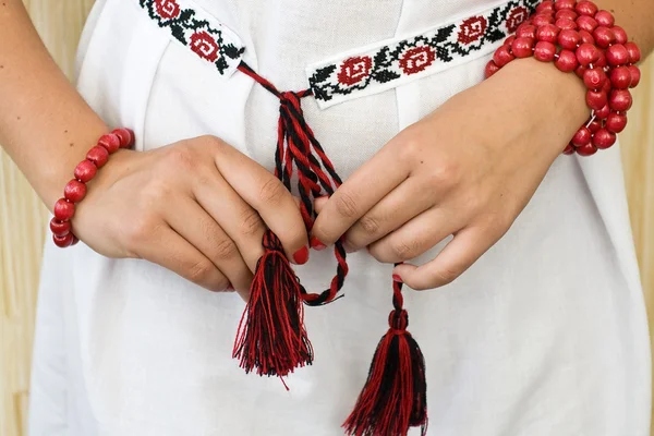 Mains de fille avec bracelets rouges et chemise brodée traditionnelle — Photo