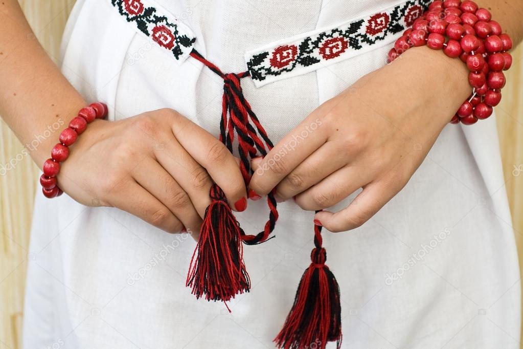 Girl's hands with red bracelets and traditional embroidered shirt