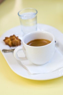Espresso, bir bardak su ve beyaz bir tabak kurabiye