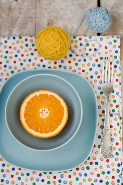 Soczysta pomarańcza leżącego na niebieski płyta z jasnej tkaniny na tle drewniane — Zdjęcie stockowe