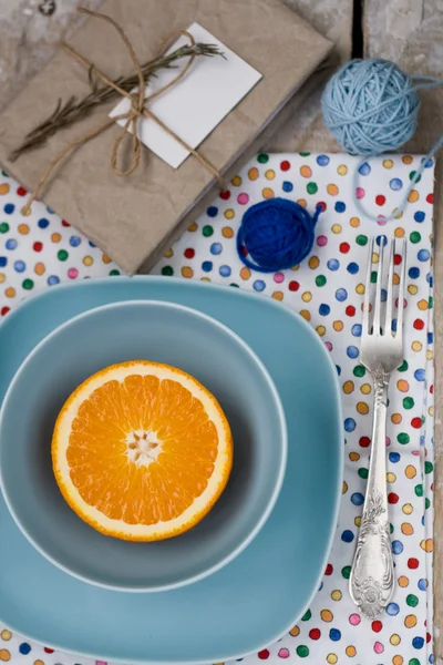 Saftige Orange auf blauem Teller ist das alte Pad und Garngewirr — Stockfoto