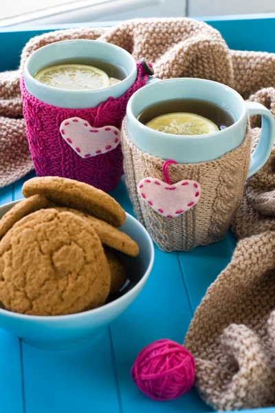 Due tazze di tè blu in maglione lavorato a maglia con cuori feltro in piedi — Foto Stock