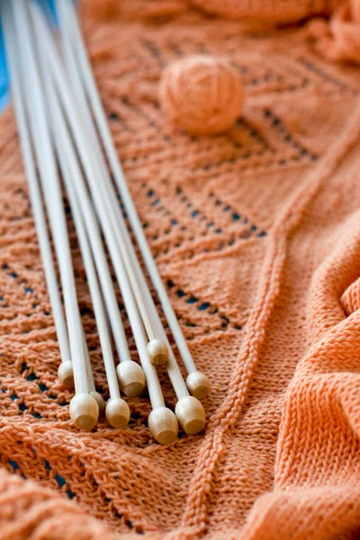 Viele Holzspeichen liegen auf einem orangefarbenen Strickkleid — Stockfoto