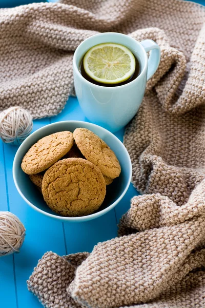 A cup of tea with lemon, biscuits, beige knitted blanket  lie on — Stock Photo, Image