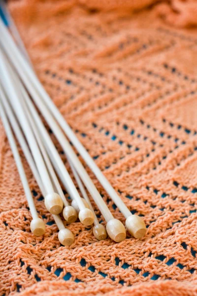 Viele Holzspeichen liegen auf einem orangefarbenen Strickkleid — Stockfoto