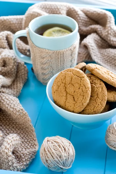 Eine Tasse Tee mit Zitrone, Kekse, beige Strickdecke liegen auf — Stockfoto