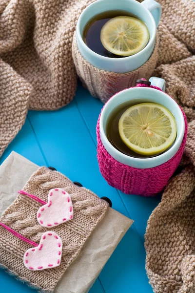 Two blue cup of tea in knitted sweater with hearts felt standing — Stock Photo, Image