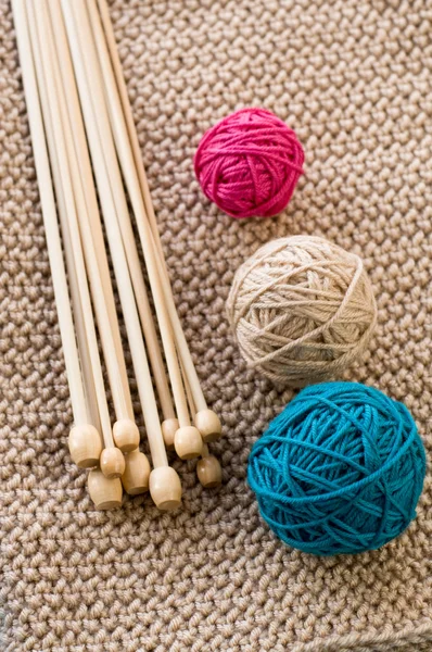 Tres bolas de colores y agujas de madera que yacen en punto beige p —  Fotos de Stock