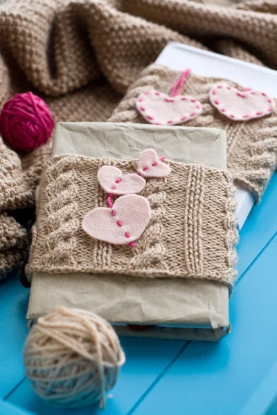 Two old pads in knitted cover with felt hearts lie next to the c — Stock Photo, Image