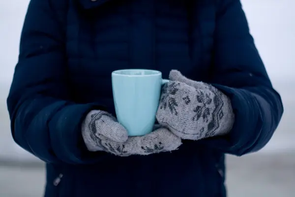 Meisje in blauwe jas en handschoenen houden een blauwe kopje thee — Stockfoto