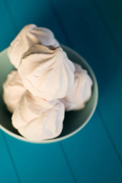 Zarte rosa Marshmallows liegen im blauen Teller auf blauem Backgr — Stockfoto