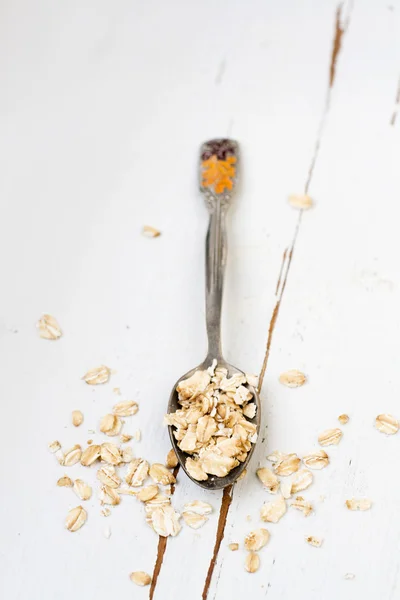 One tablespoon of oatmeal is a white wooden background. Healthy — Stock Photo, Image