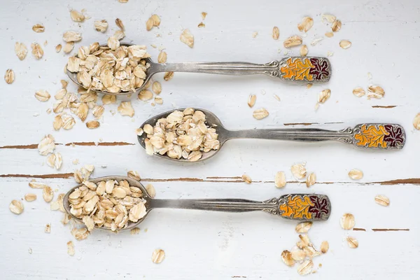 Tres cucharadas de avena sobre un fondo de madera blanca . — Foto de Stock